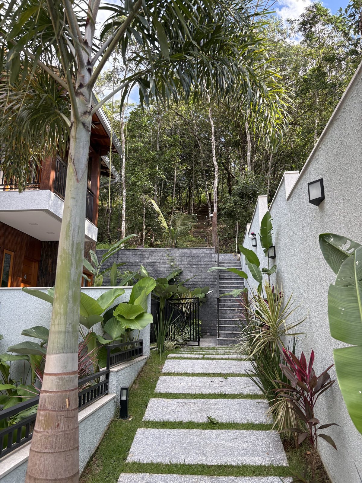 Caminho ajardinado entre palmeiras e vegetação nativa da Vila Jardim