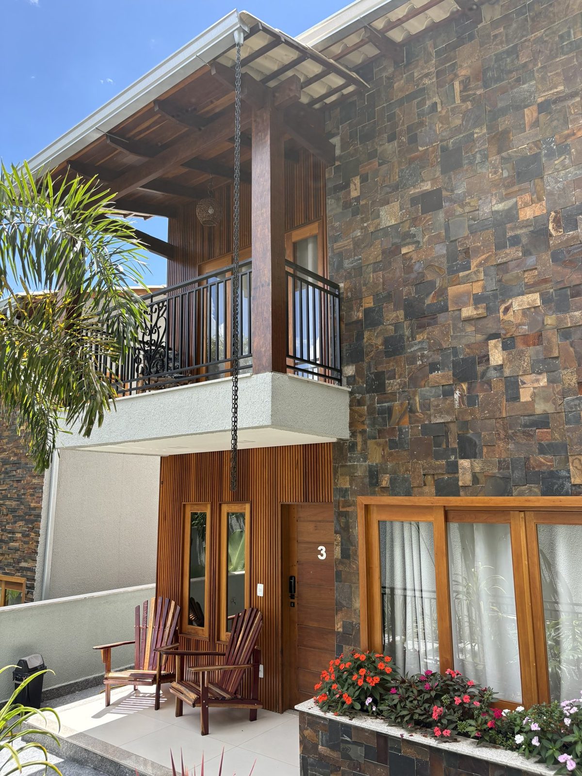 Fachada de chalé com varanda de madeira e canteiro de flores